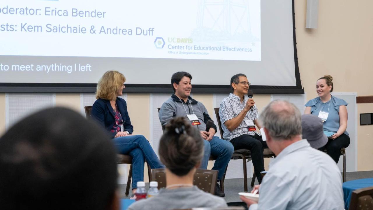 A panel of four speakers addressing a crowd