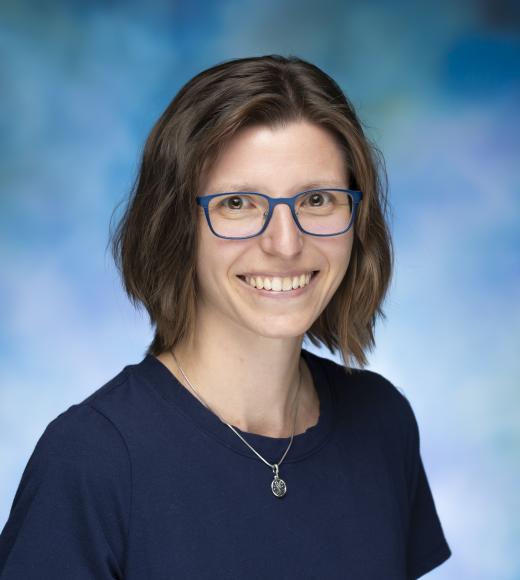Smiling woman with blue glasses and navy top.