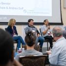 A panel of four speakers addressing a crowd